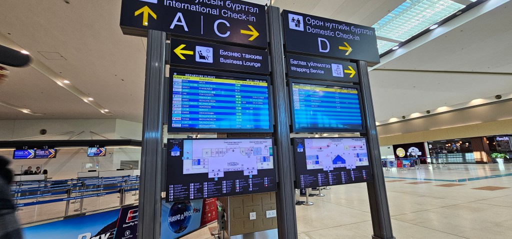 Airport information display with check-in signs for international and domestic flights, showing flight statuses and terminal maps.