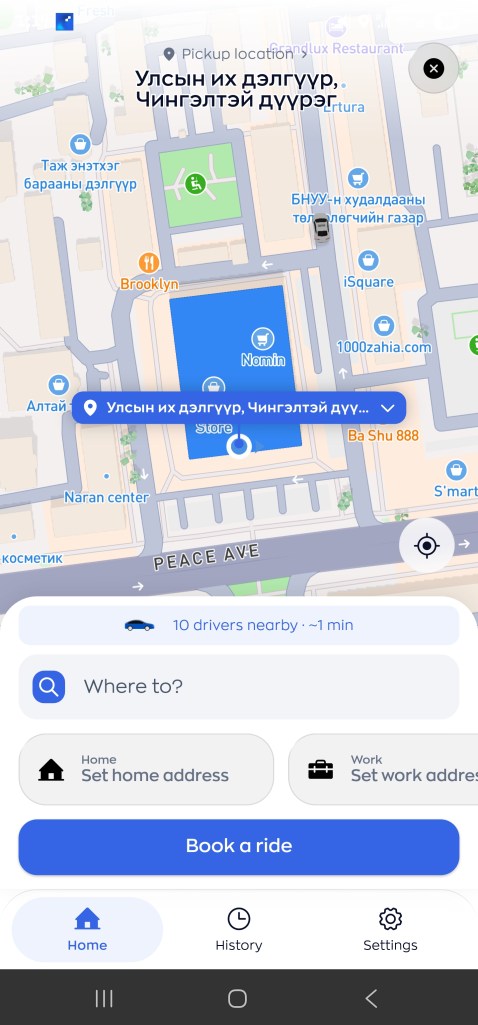 Map view showing a city layout with streets and nearby locations, featuring a blue square labeled 'Nomin', pickup options for a ride, and an input field for destination address.