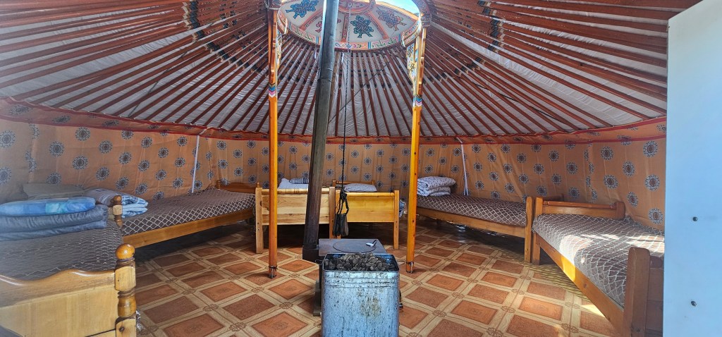 Interior of a yurt with wooden beds and colorful patterned walls.