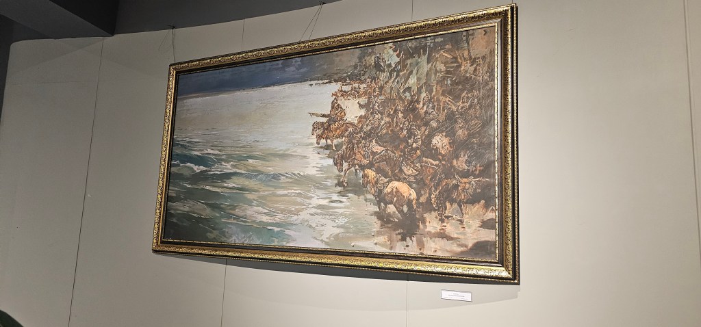 A large framed painting depicting a serene landscape with a river and a group of animals near the water's edge.